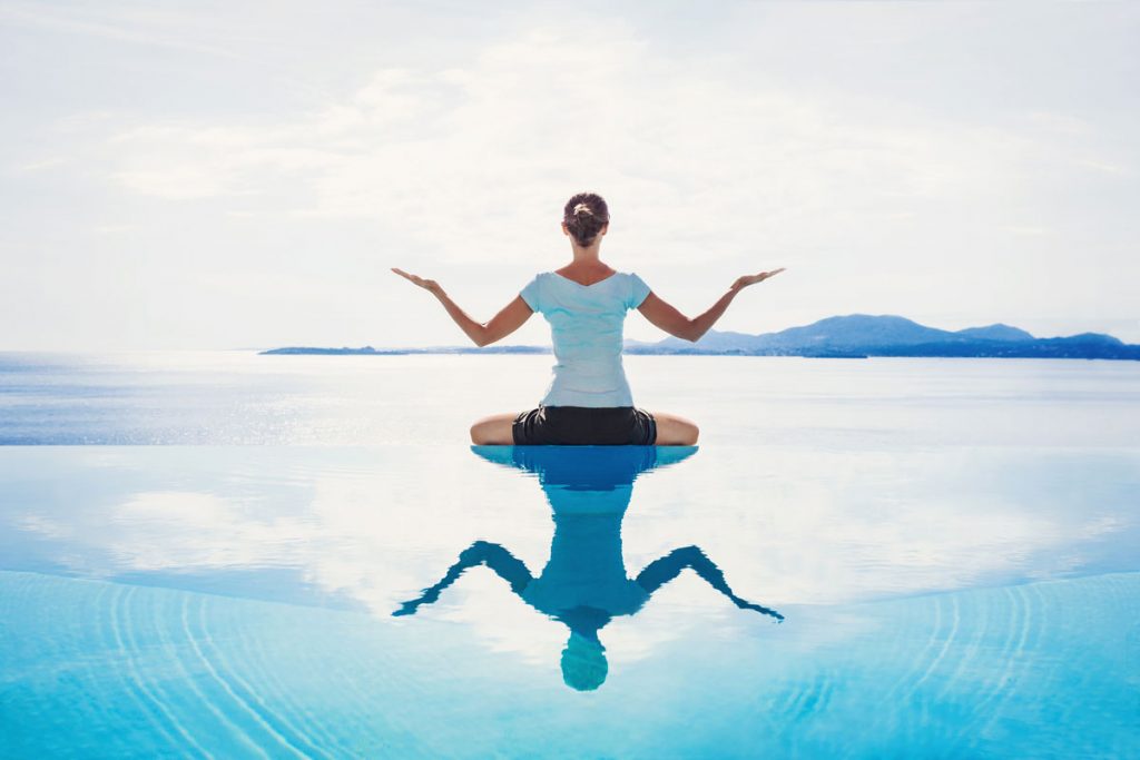 A woman meditating over the ocean, finding inner peace, happiness.