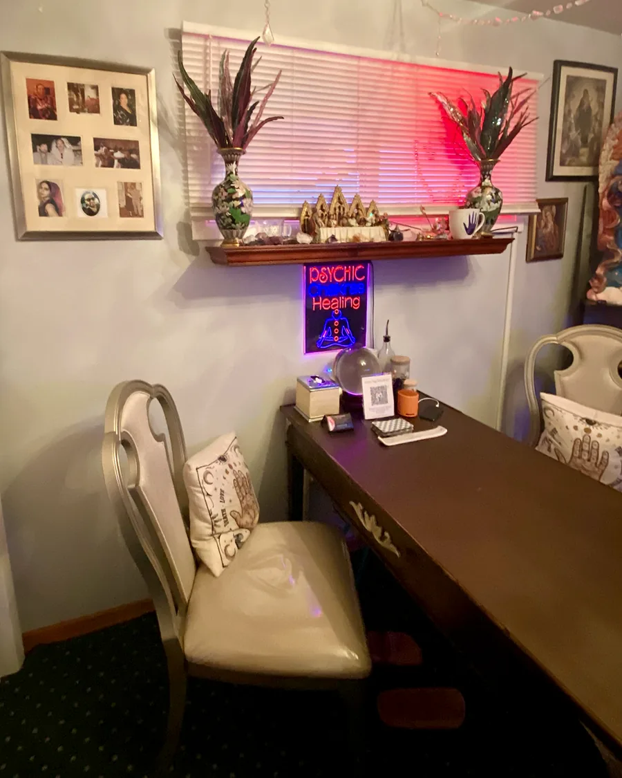 The reading room at Psychic Ames in Gurnee with a desk, crystal ball and warm pink window light